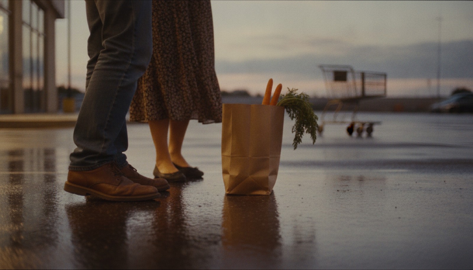 Two pairs of shoes mid-turn on wet parking lot asphalt beside a paper grocery bag