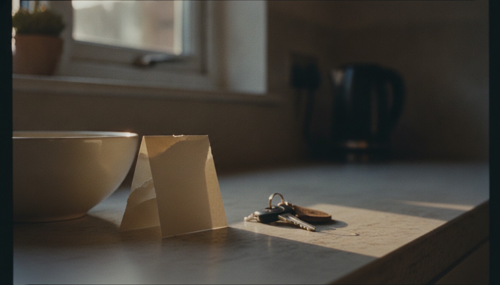 A handwritten note folded on a kitchen counter beside a set of car keys in early evening light