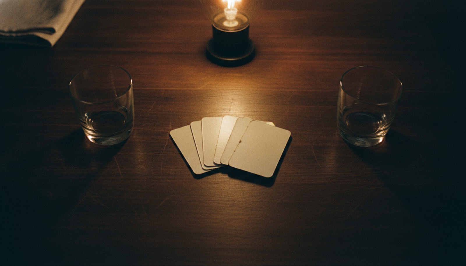 A banded stack of face-down cards resting on a dining table between two water glasses after dinner